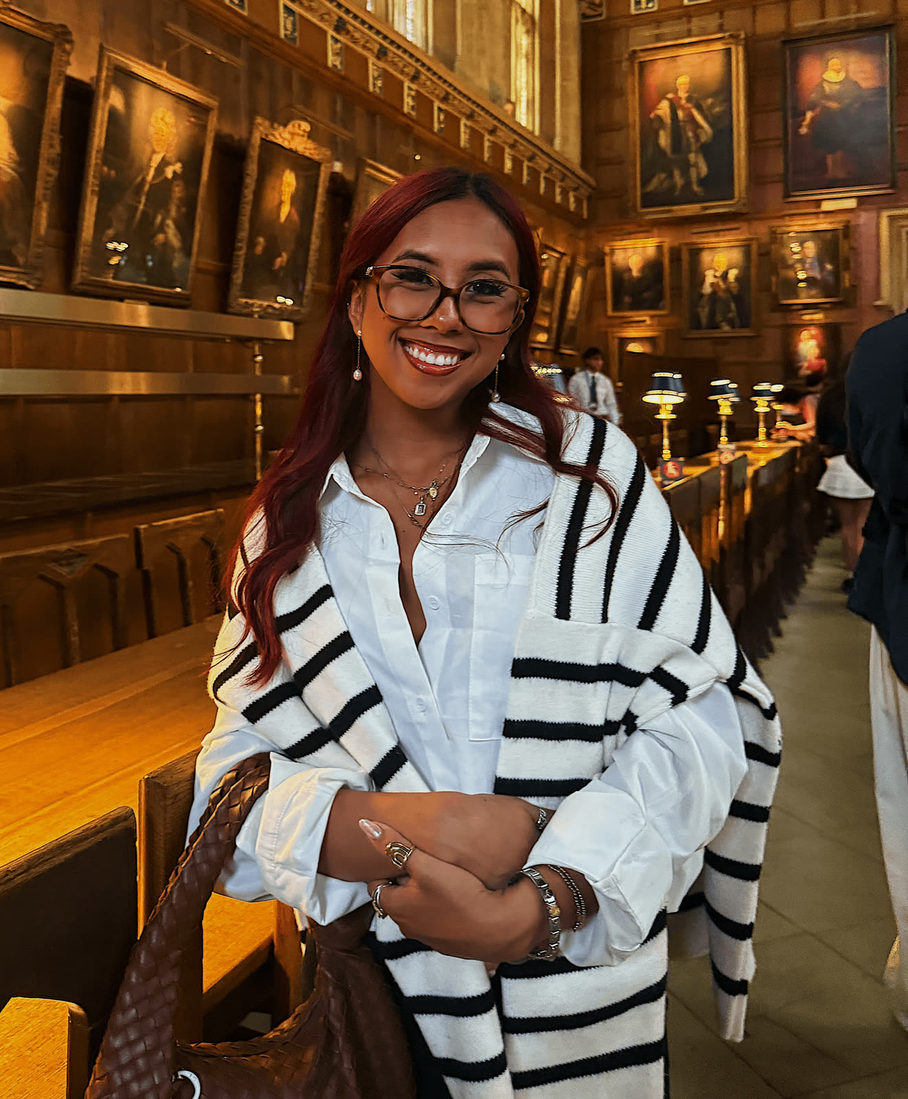Melodi laughing in a striped shirt at a golden-lit dinner table
